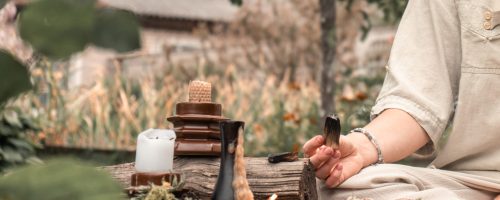 Méditation. Femme inhalant de la fumée d'encens pendant la méditation. Niveau au sol d'une femme détendue méditant et respirant tout en étant assise dans une pose de lotus près de l'encens parfumé pendant une séance de yoga dans le jardin